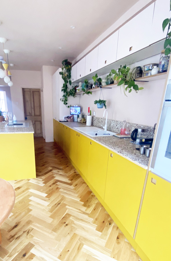 plywood kitchen with yellow base units and pale pink overhead cabinets